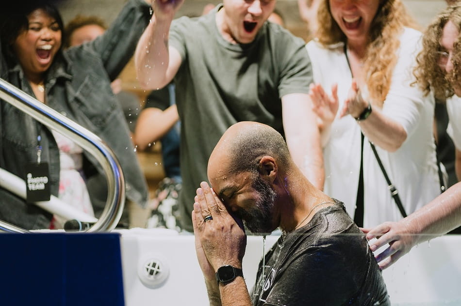 A man is baptized while friends cheer behind him