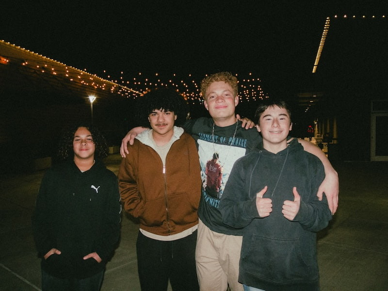 A group of friends outside at night under string lights
