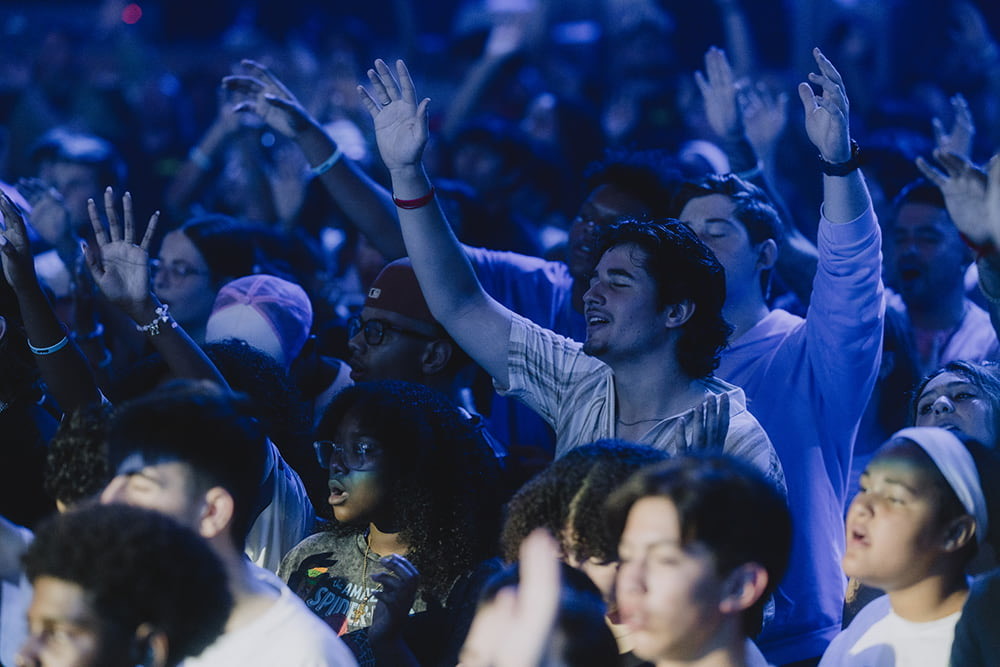 A crowd worshiping with hands raised